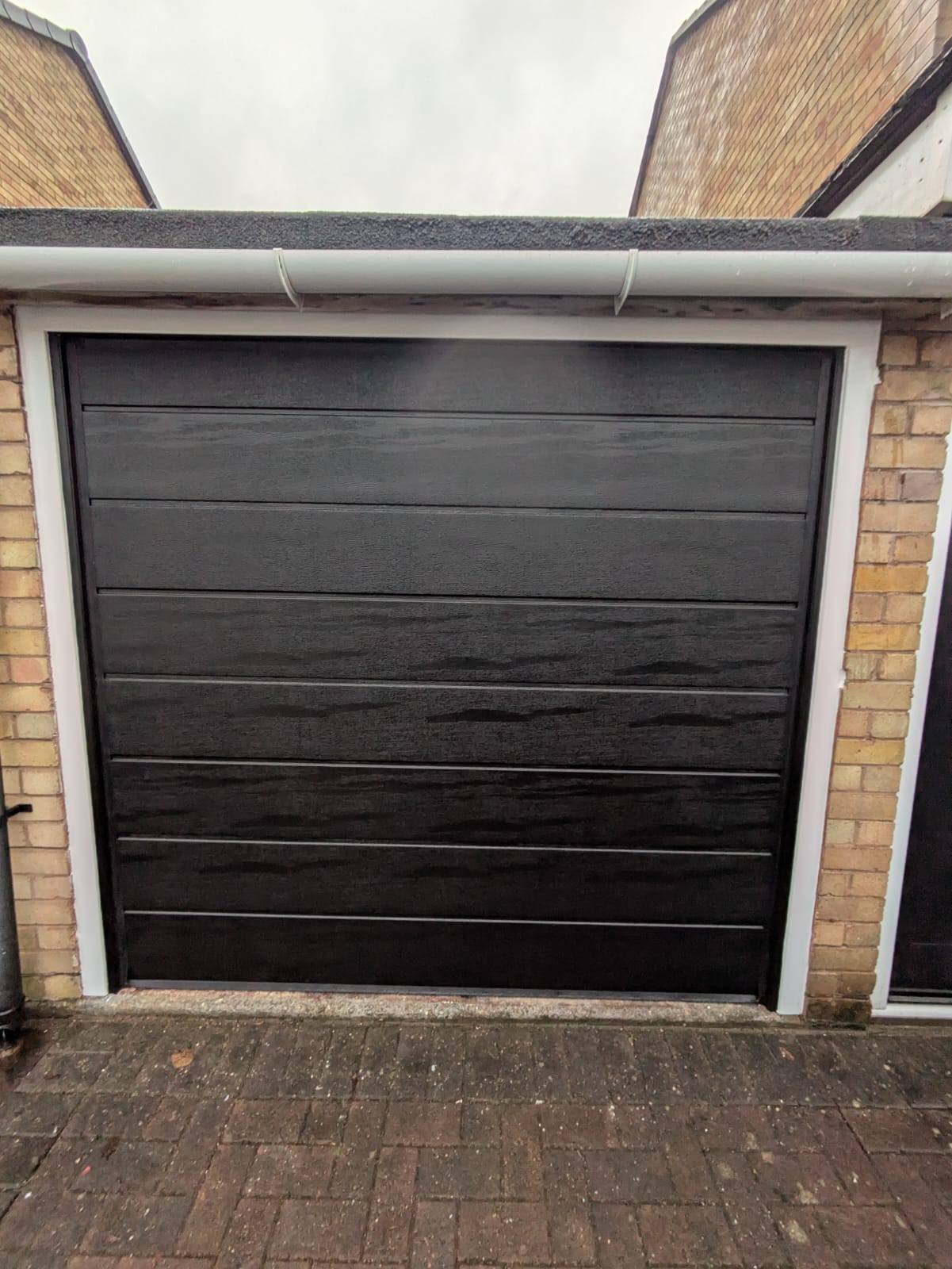 Small black automatic sectional garage door in Telford